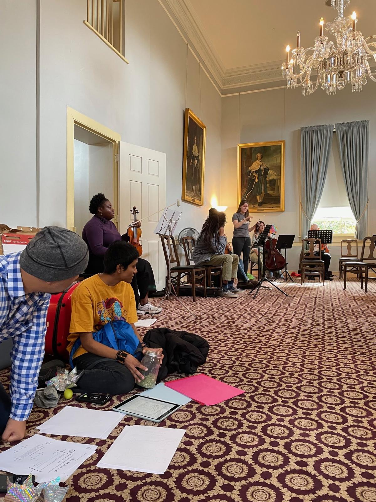 Attendees sit along the wall of a fancy colonial style decorated room
