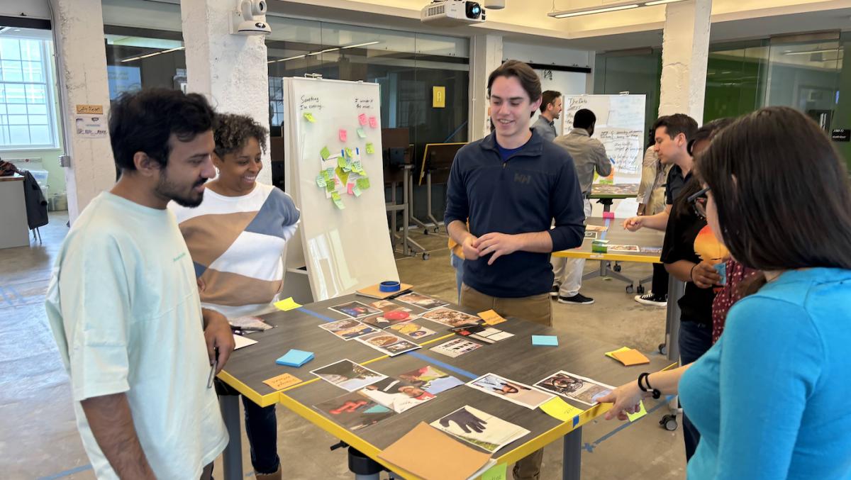 Four people standing around a table smiling as they look at photos on the table