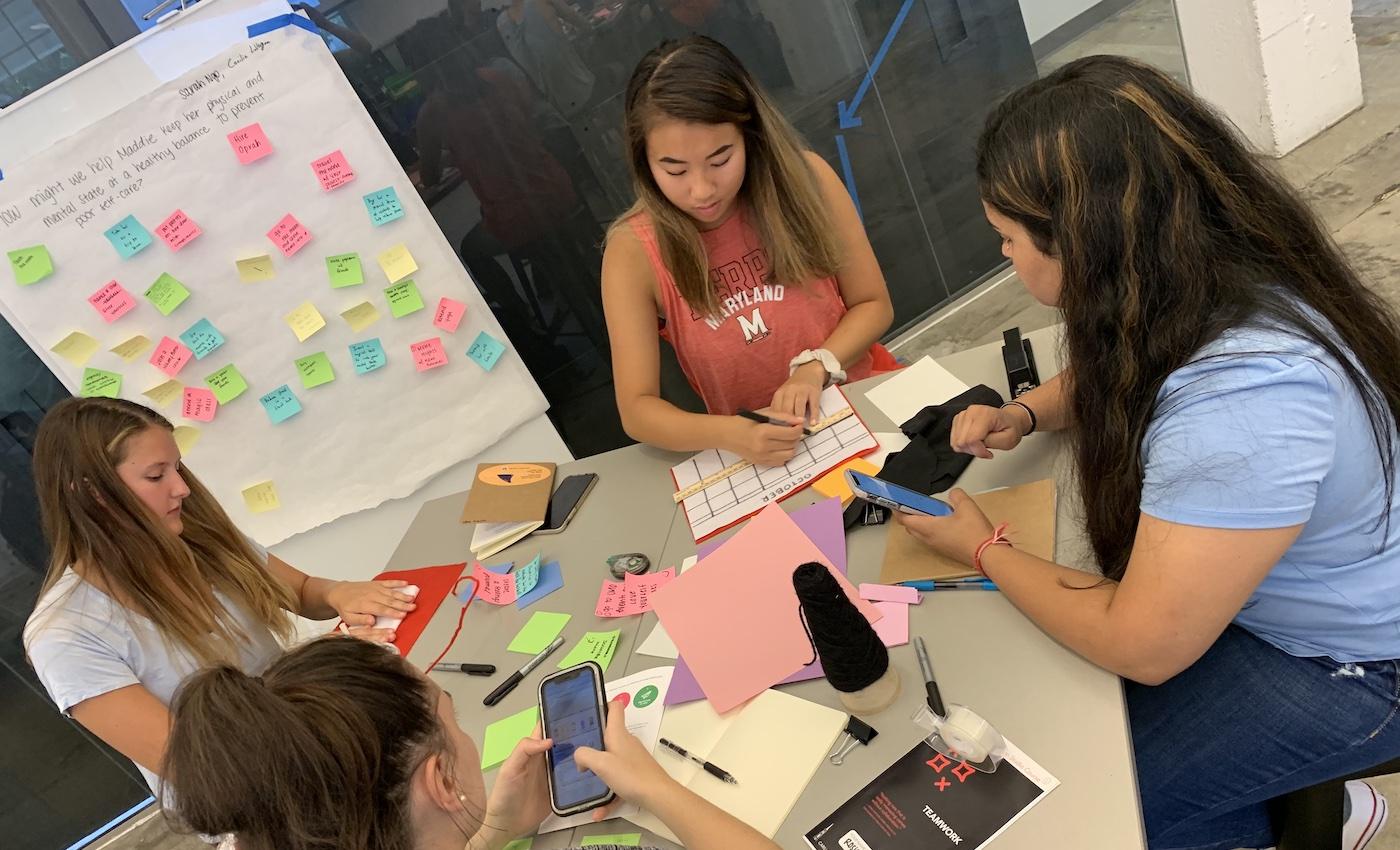 Four students sitting around a table making low resolution prototypes out of paper and felt