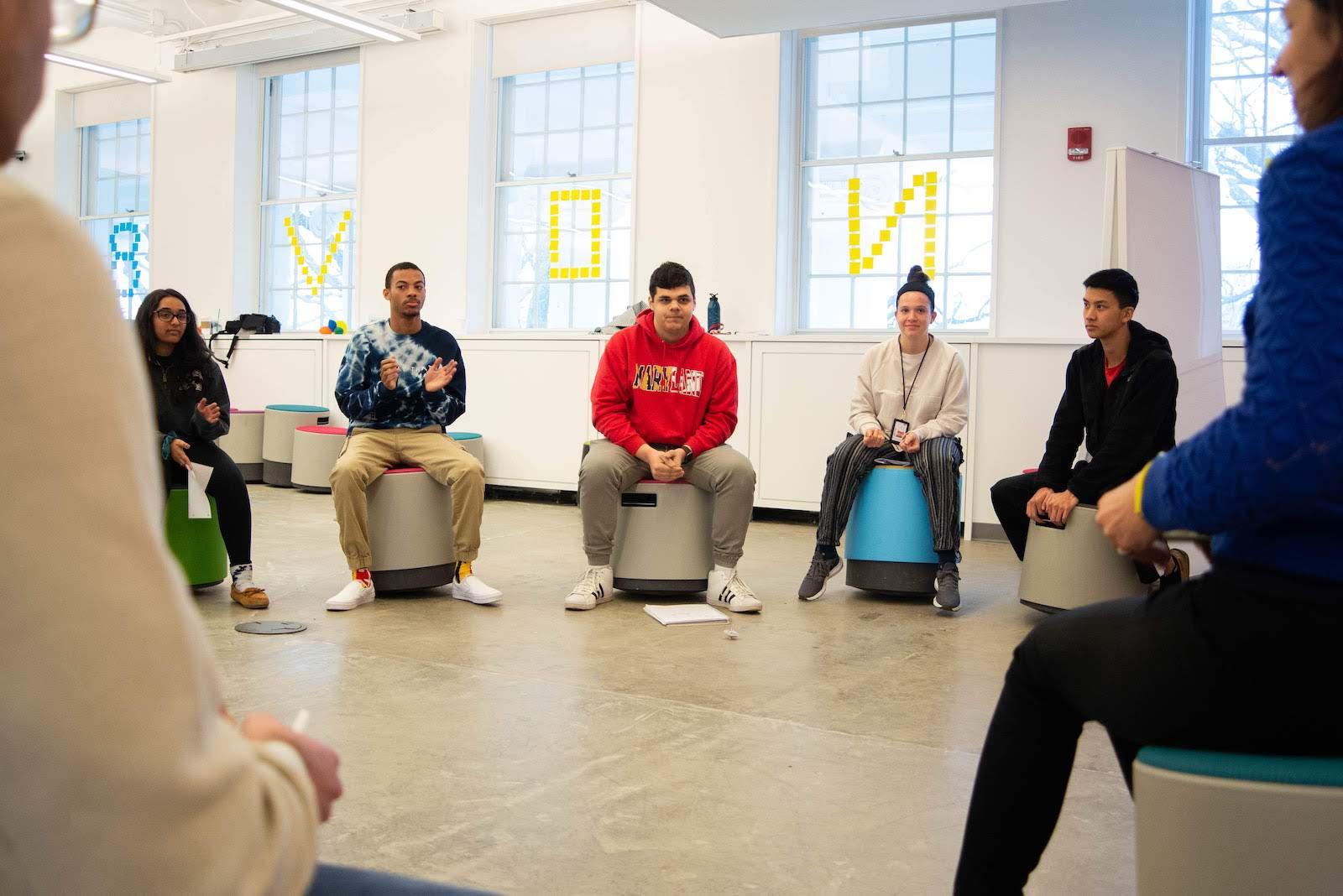 Students sitting in a circle on wobbly stools listening