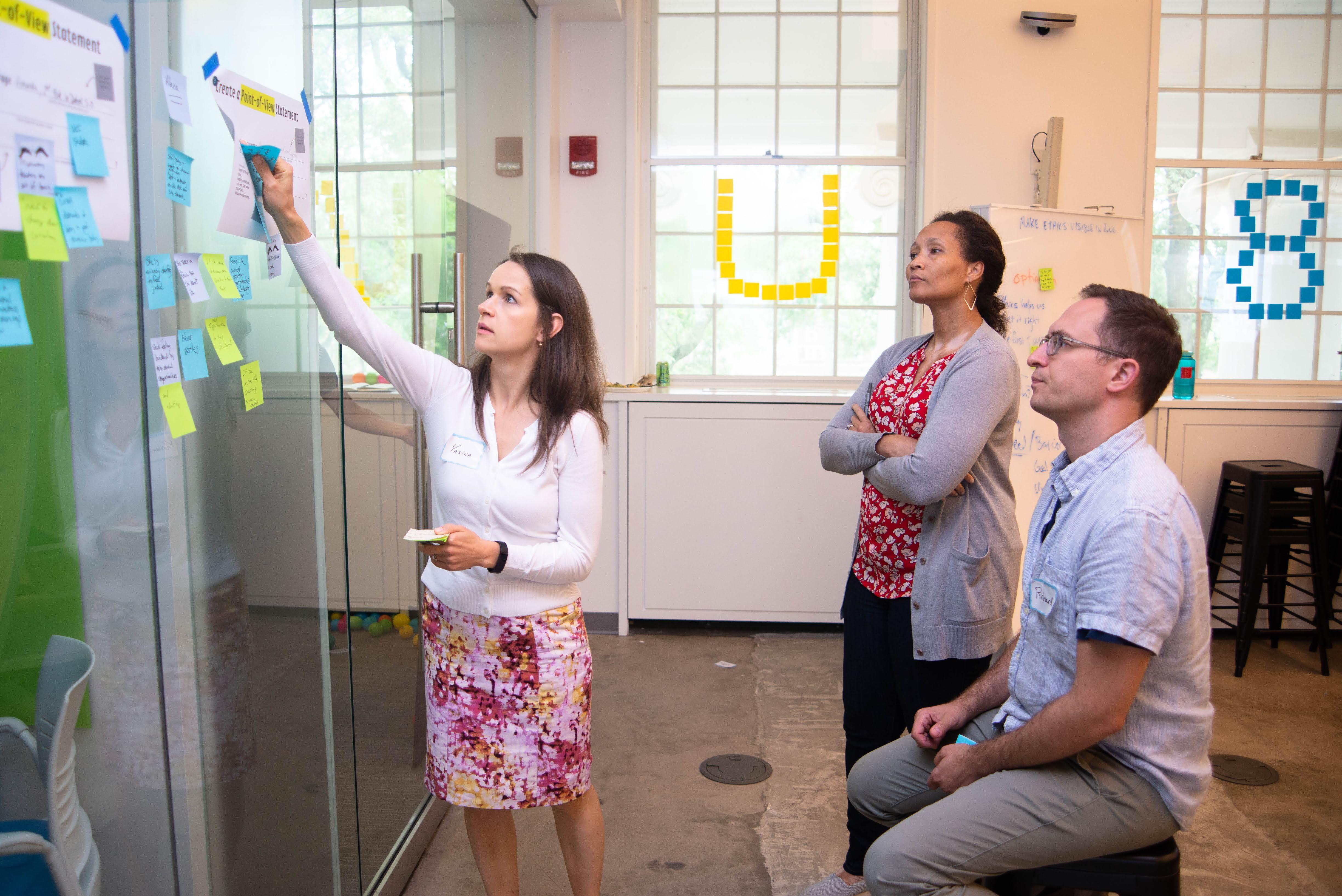 Faculty putting post-it on a wall 