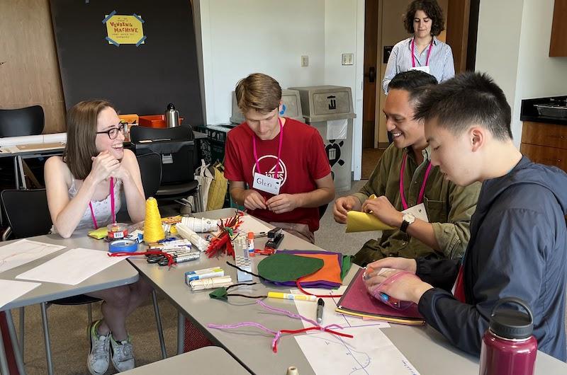 Students sitting at a table making low-resolution prototypes out of construction paper
