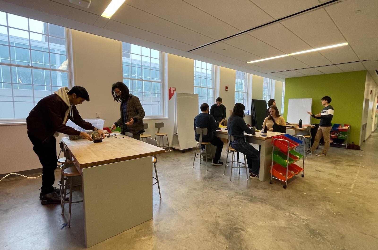 Small groups of students collaborating together a tables in an open space