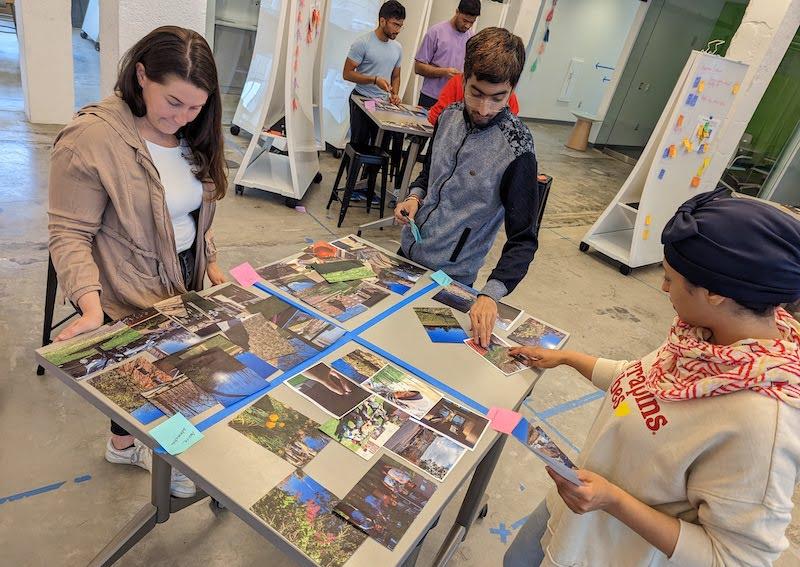 Three students standing around a table organizing photos