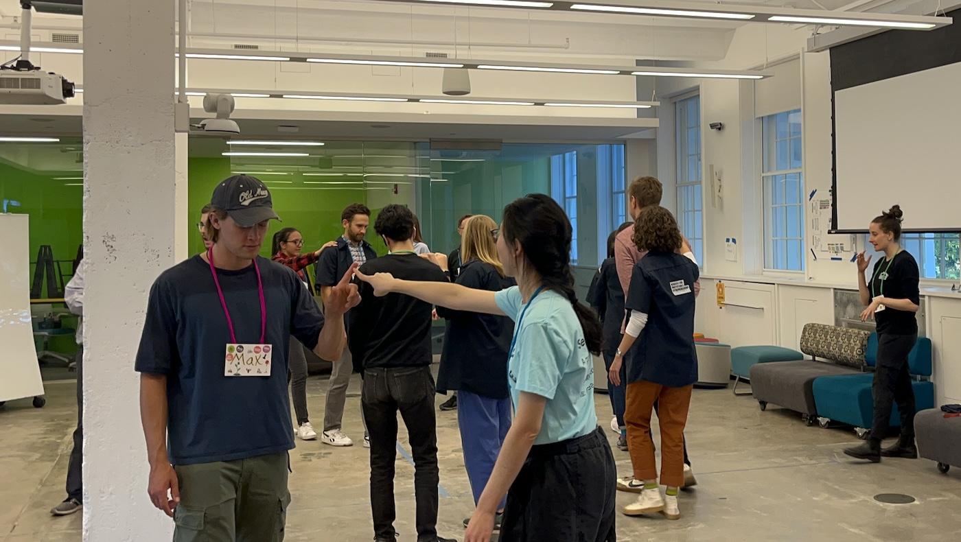 People walking around a loft space with their eyes closed while touching hands