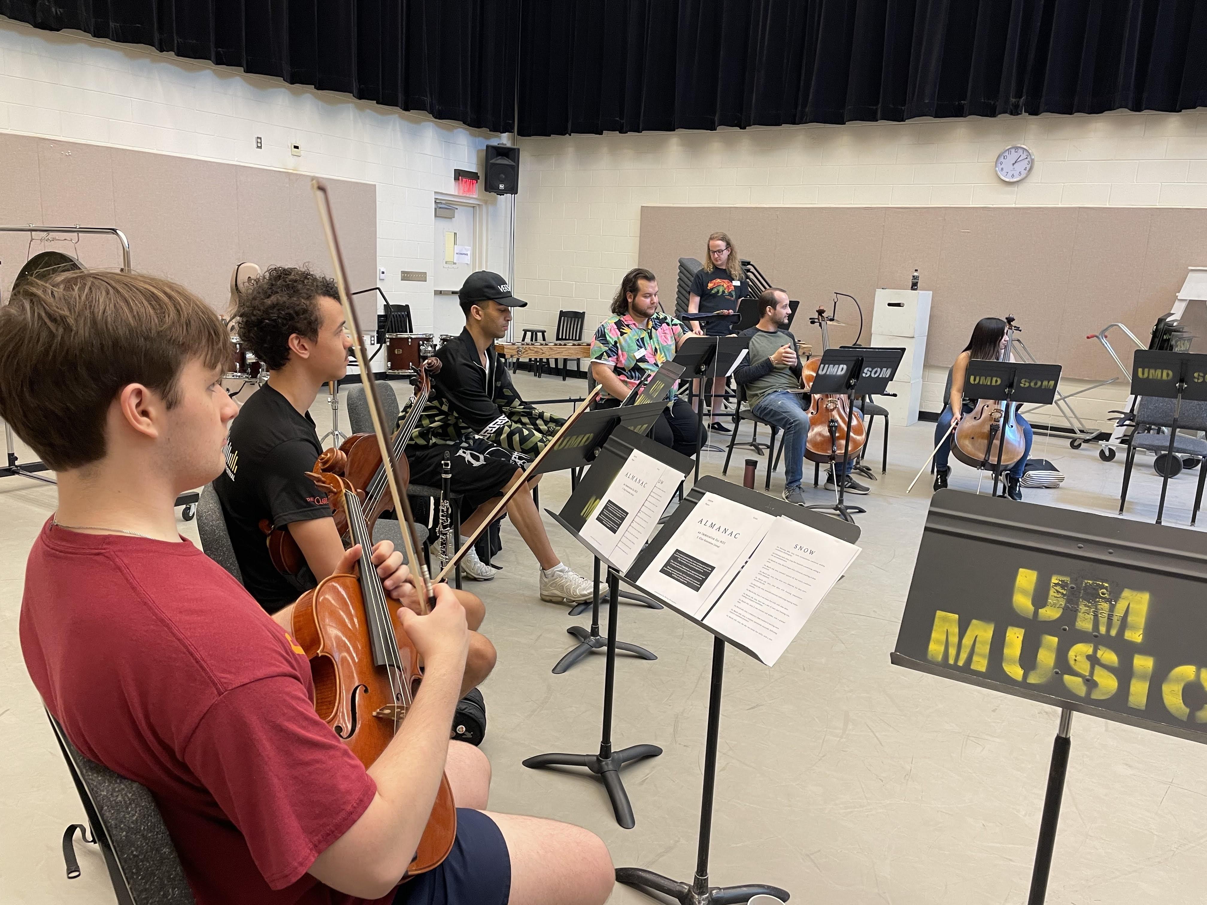 Musicians sit in a U-shape with instruments
