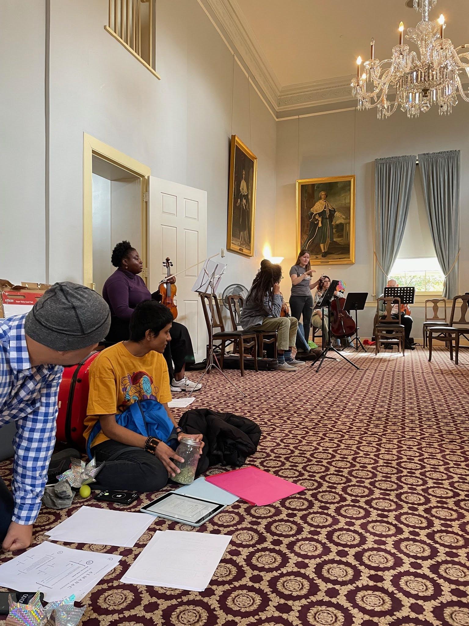 Attendees sit along the wall of a fancy colonial style decorated room