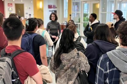 Students standing in a lobby listening to an instructor